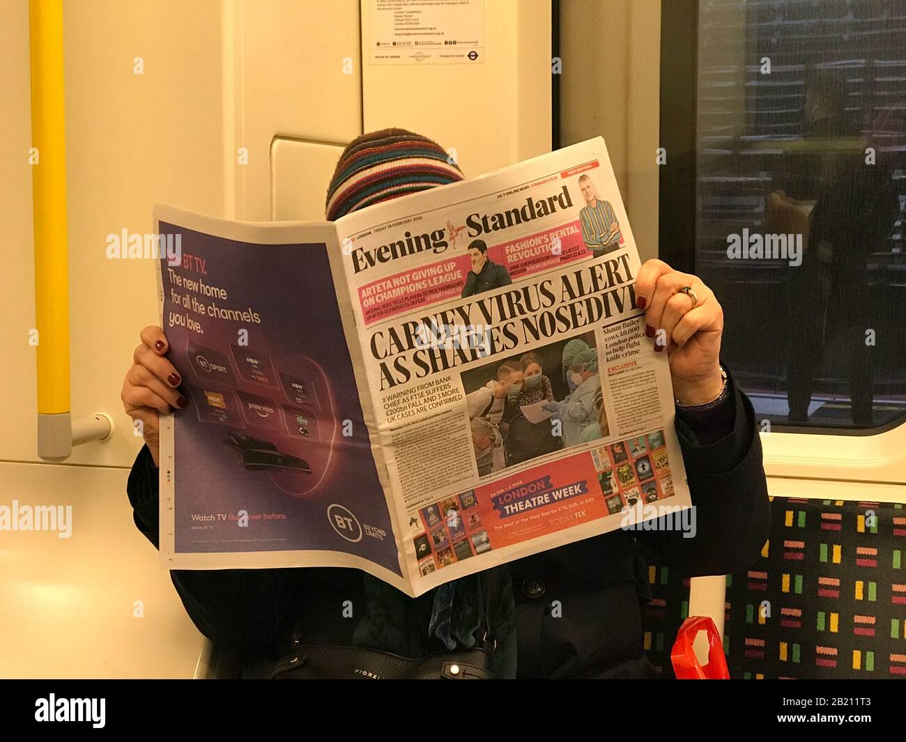 Coronavirus : un passager du métro de Londres lit les gros titres du coronavirus dans le journal du soir pour Londres Banque D'Images