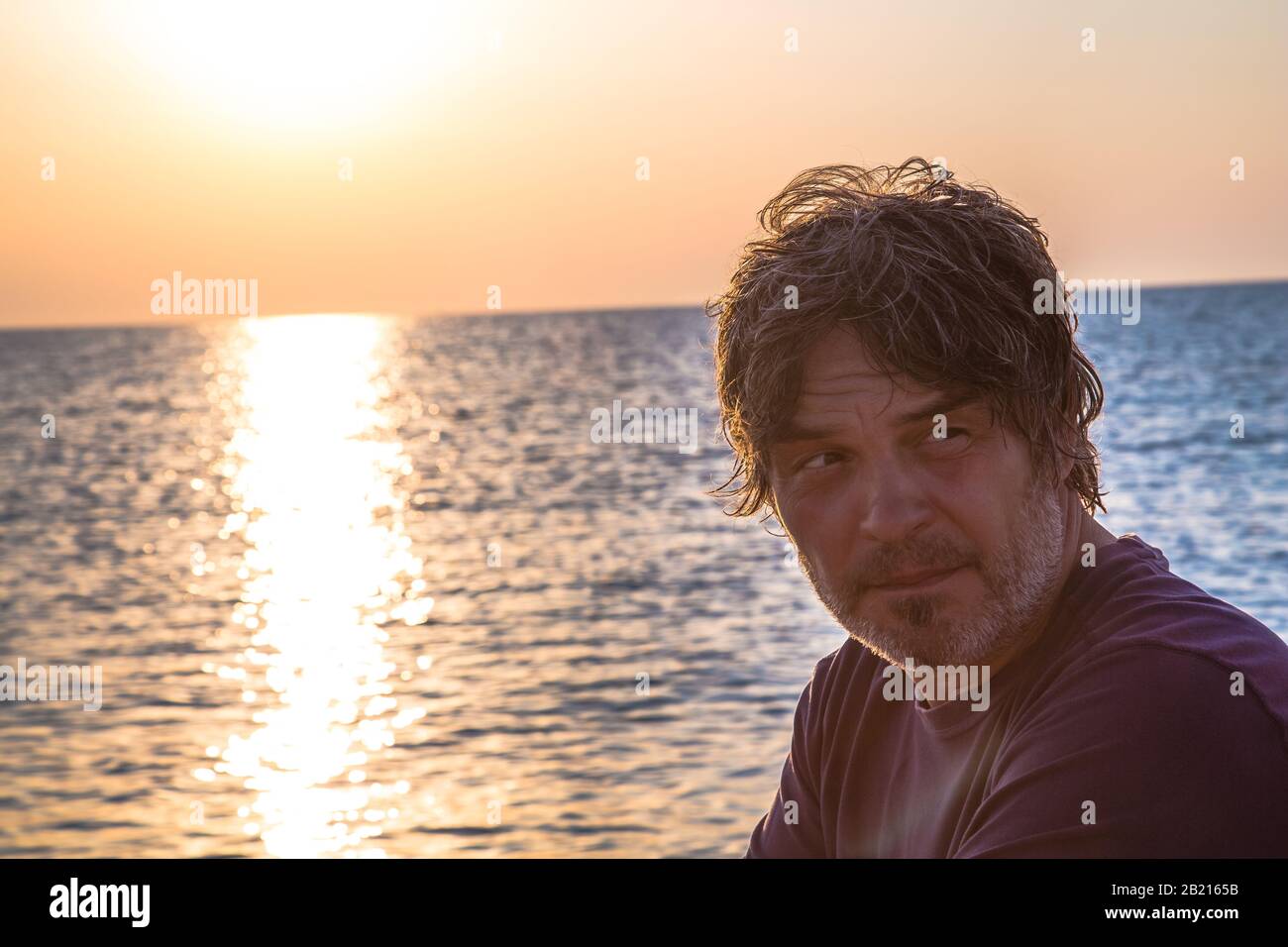 Bel homme avec un look lointain / Portrait de bon homme d'âge moyen sur la plage pendant les couchers de soleil Banque D'Images