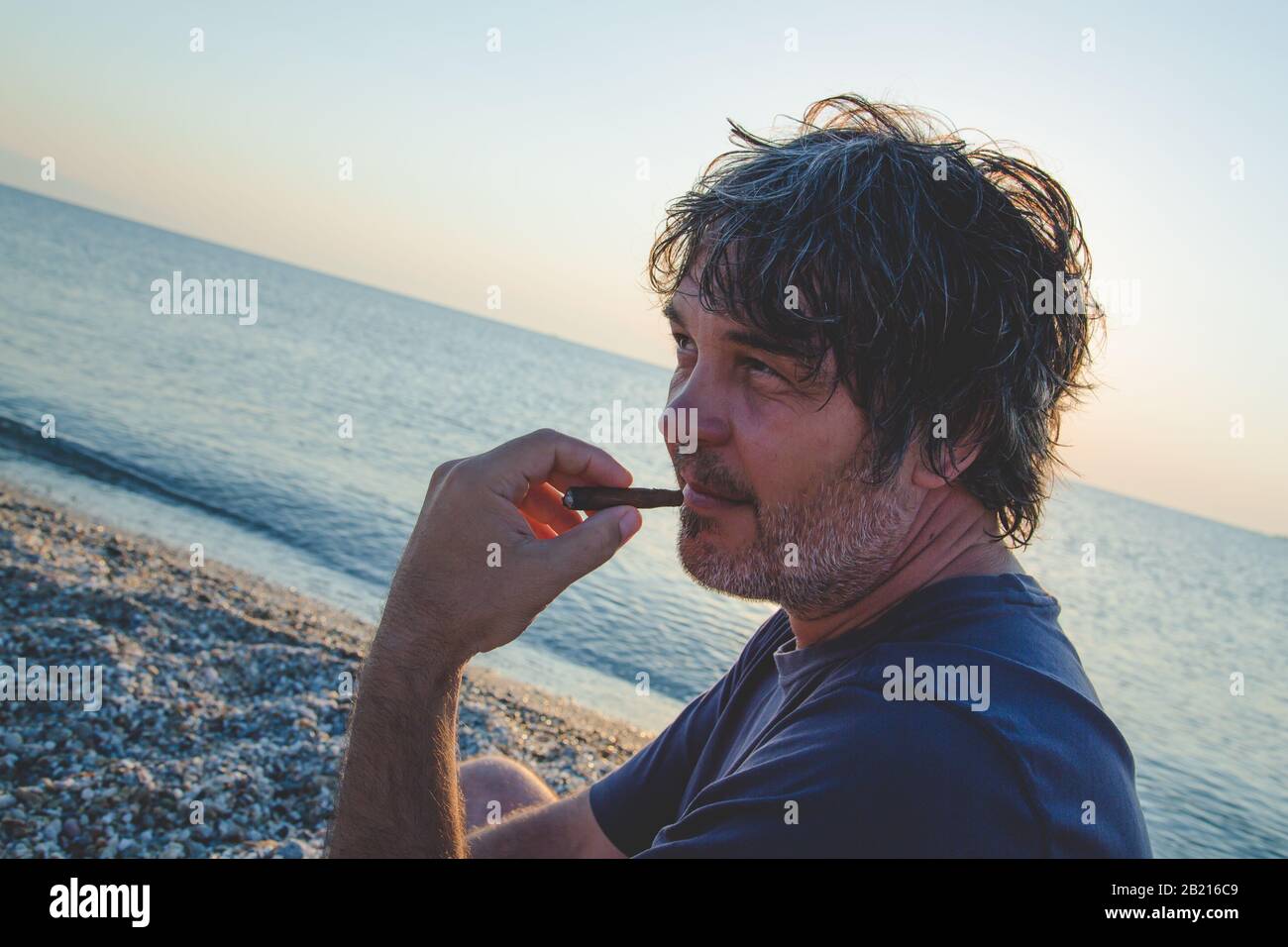 Portrait de bon homme d'âge moyen avec un cigare / coucher de soleil. Gros plan Banque D'Images