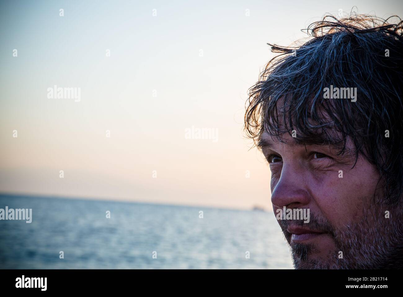 Homme d'âge moyen sur la plage alors que couchers de soleil / gros portrait Banque D'Images