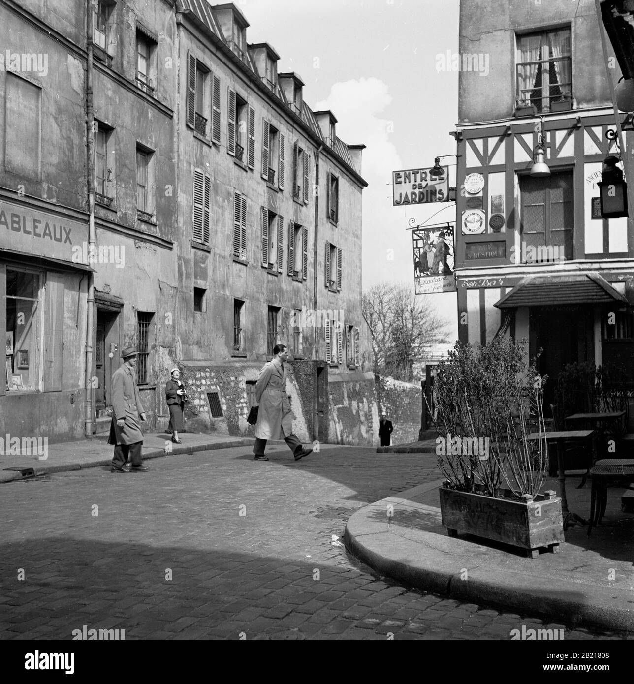 Années 1950, Paris, France, rue pavée et bâtiments dans le quartier Montmartre de la ville parisienne, célèbre pour ses artistes de rue et son église, le Sacré coeur. L'image montre le coin de la rue des Saules et de la rue S. Ristque et le restaurant, l'entrée des Jardins. Banque D'Images