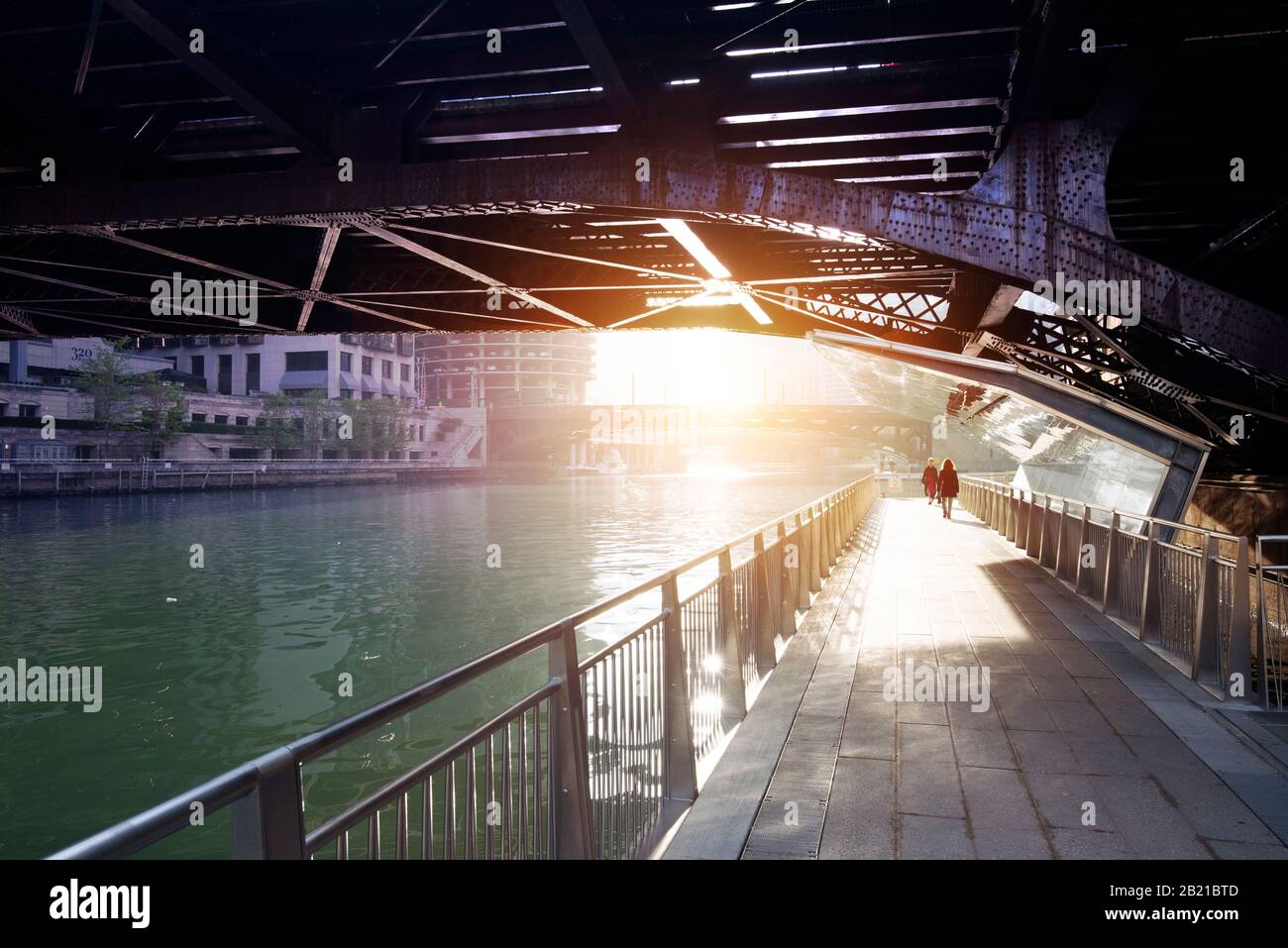Vue sur la promenade de la rivière Chicago depuis sous un pont, face à l'éblouissement du soleil du matin avec des figures lointaines Banque D'Images