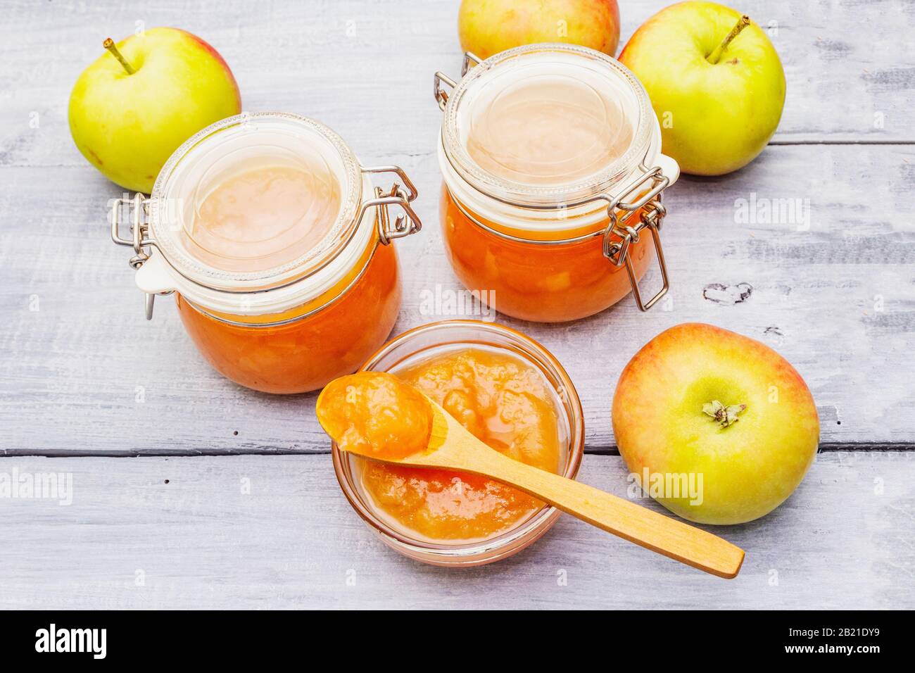 Confiture de pommes, confiture, chutney dans un pot en verre. Concept de préservation maison. Avec des pommes fraîches, cuillère rustique sur fond de planches en bois gris Banque D'Images