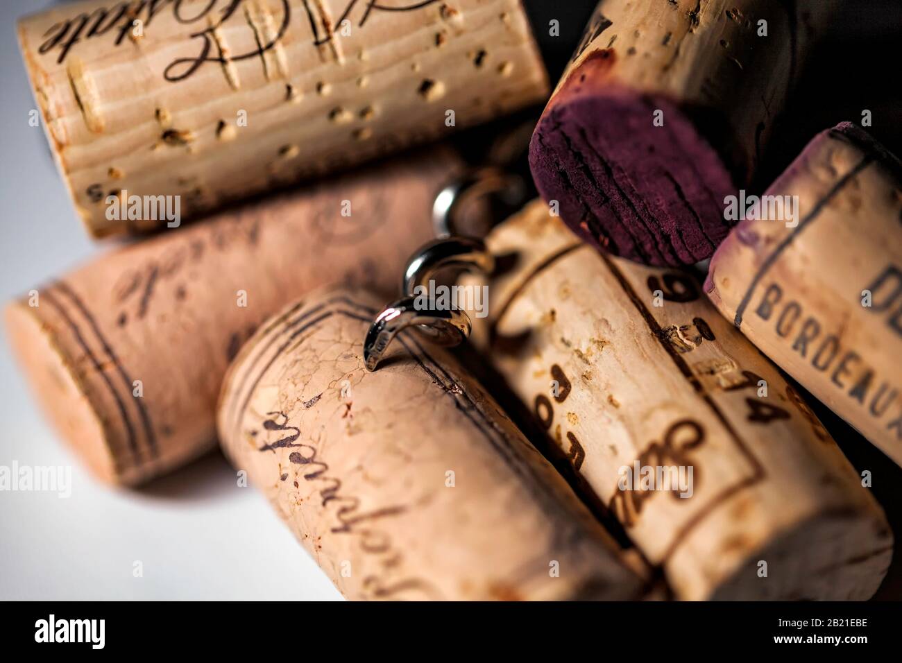 Tire-bouchon reposant sur et entouré de bouchons de couleur de vins européens Banque D'Images