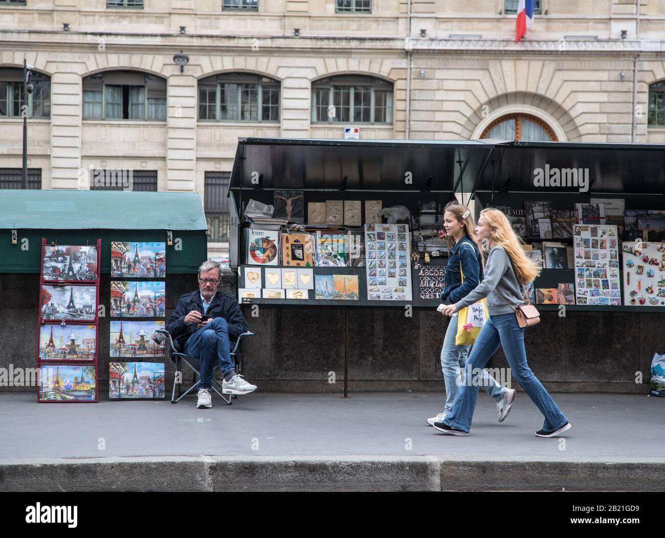 Paris, France - 2 octobre 2019: Les touristes marchant devant Des Étals vendant des cartes postales et des reproductions le long des rives de la Seine sur le Quai du Louvre Banque D'Images