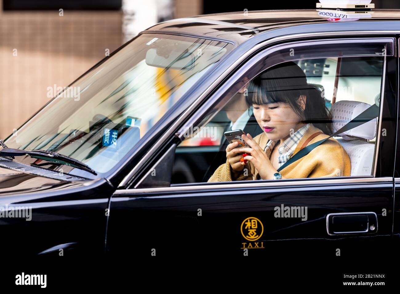 Kyoto, Japon - 17 avril 2019: Rue du centre-ville avec une jeune fille locale qui monte taxi noir dans la circulation de proximité texting au téléphone Banque D'Images