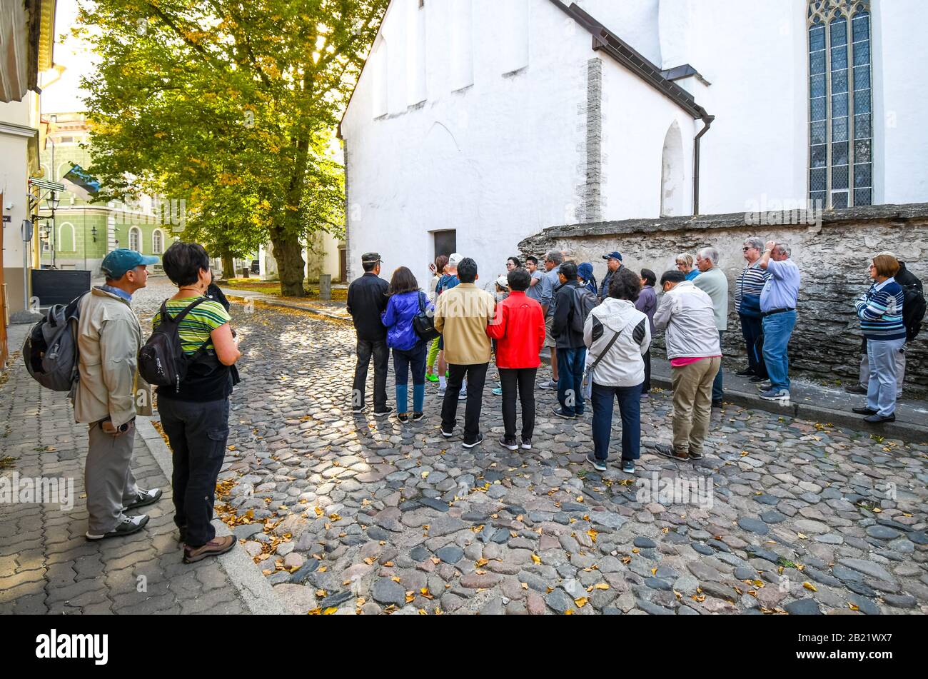 Un groupe de visites s'interrompt pour écouter un guide touristique dans une rue pavée de la vieille ville médiévale de Tallinn Estonie. Banque D'Images