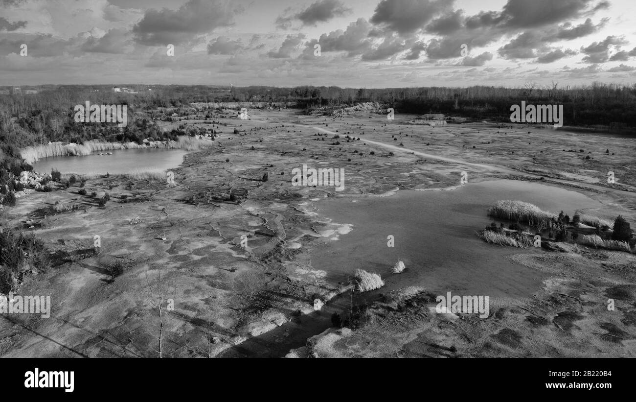 Carrière De Rock Abandonnée Au Coucher Du Soleil. Vue de haut au-dessus d'un plan stérile. Étangs et plan mort noir et blanc Banque D'Images