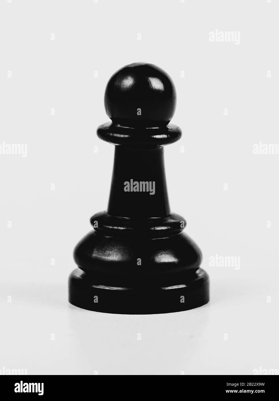 Un seul pion noir brillant d'échecs isolé, mat, faible contraste. Un seul morceau d'échecs sur fond gris, macro, résumé. Jeu d'échecs Univers Banque D'Images