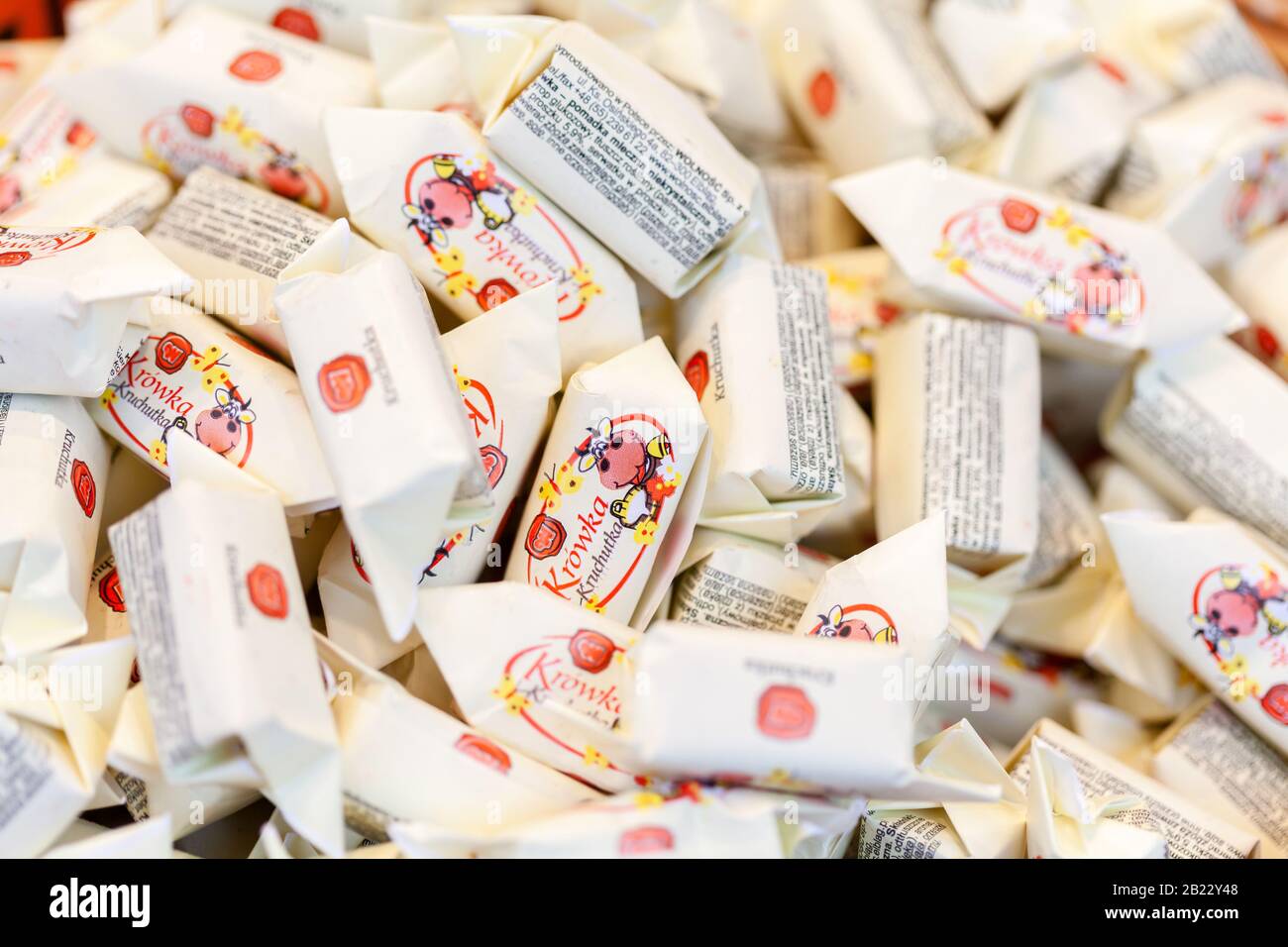 Un tas de petites bonbons polonais fudge traditionnels emballés dans la macro de livre blanc, closeup. Beaucoup de friandises sucrées, surface de récipient de fudge, vue de dessus Banque D'Images