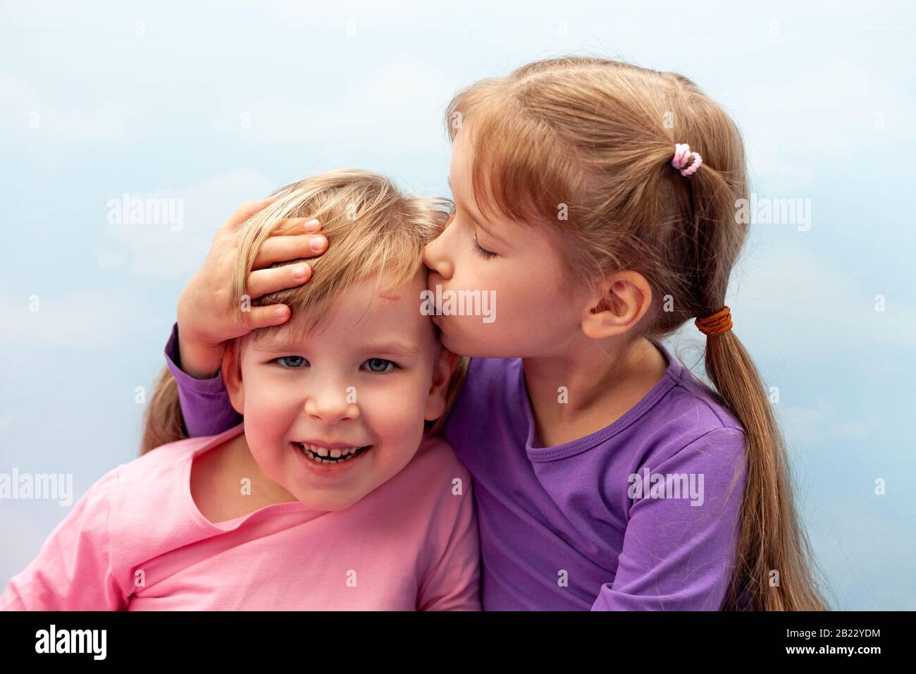 Deux petites filles, les enfants d'âge préscolaire, les jeunes sœurs fraiches éclatent, riant. Les enfants embrassent sur le concept de la tête. Soins et amour dans la famille, l'enfance Banque D'Images