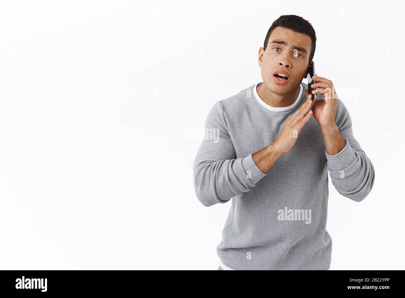 Guy étant occupé à parler au téléphone, couvrir dynamique comme vous répondre, ayant un appel important demandant d'attendre une minute. Beau homme sportif tenant smartphone Banque D'Images