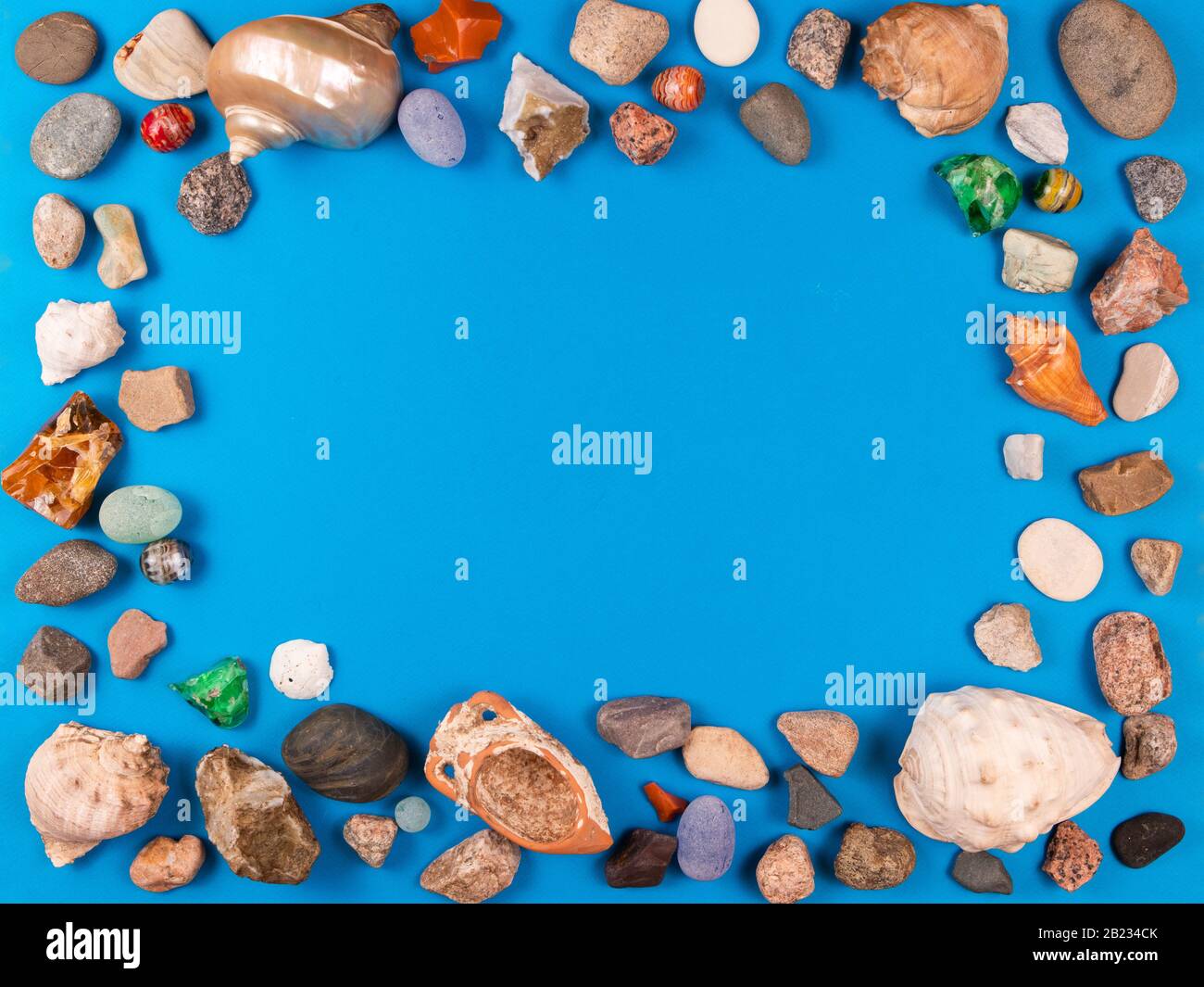 Cadre photo de coquillages et de galets sur fond bleu vif avec espace pour votre texte ou photo Banque D'Images