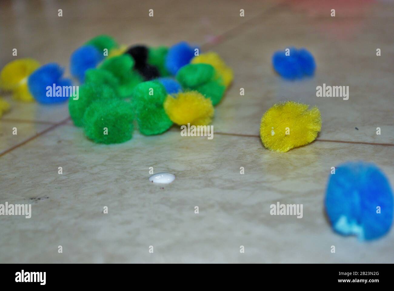 Boules de coton multicolores et colle sur un sol de linoléum pendant les arts et l'artisanat Banque D'Images