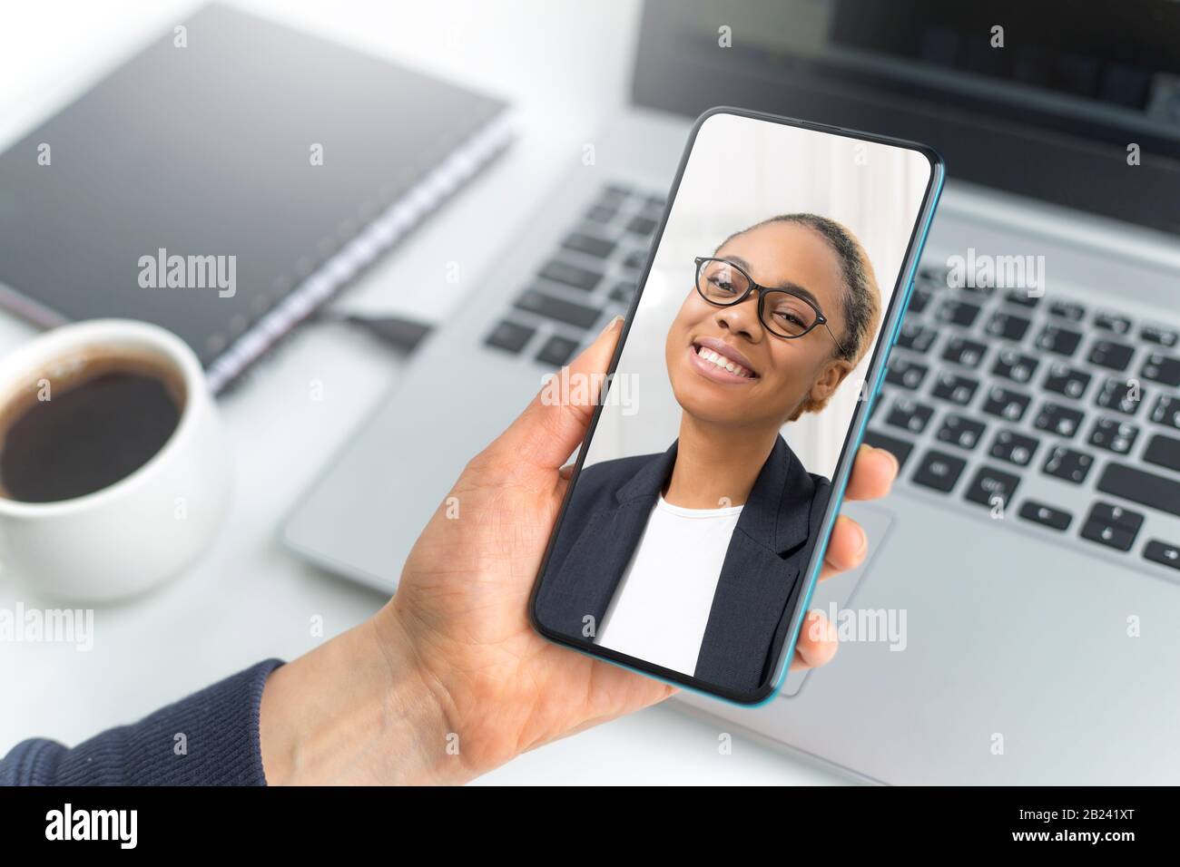 Appel vidéo en ligne via smartphone. Consultation d'affaires avec une femme africaine discutant sur écran de téléphone mobile. Banque D'Images