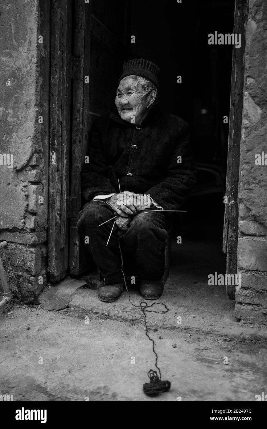 Scène de rue dans un quartier de la vieille ville de Chongqing. Vieille femme à sa porte d'entrée, Chongqing, Chine Banque D'Images