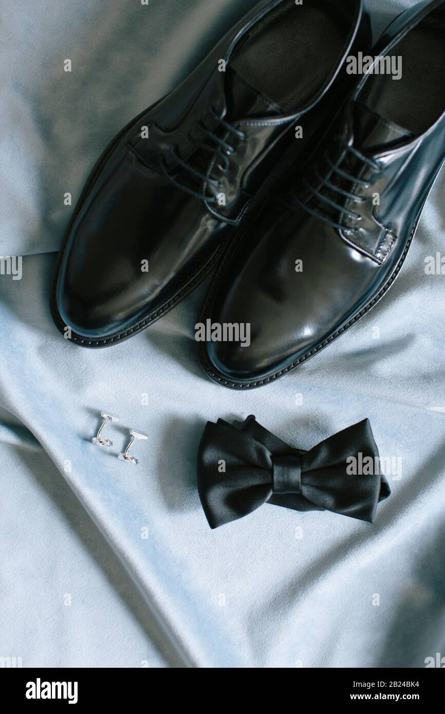 Accessoires de groom. Chaussures, noeud papillon et boutons de manchette. Sur le fond bleu. Banque D'Images