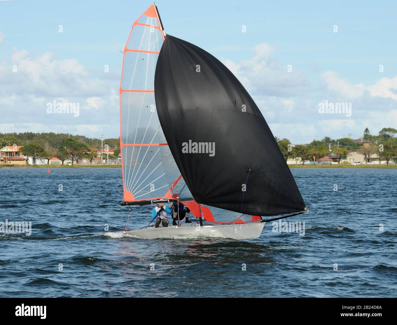 Les enfants courses un petit voilier avec un spinnaker noir à une régate junior de yachting. Travail d'équipe par des marins juniors en course sur le lac d'eau salée Macquarie. Photo Banque D'Images
