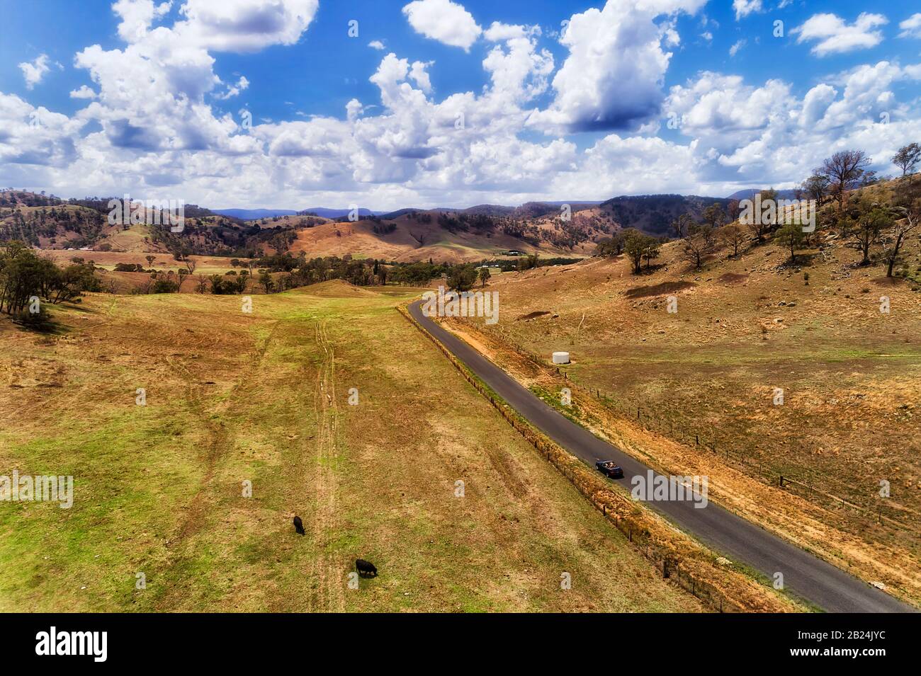 Vallée reculée dans la montagne bleue australienne couverte par des fermes de bétail coupées par la route locale avec une voiture convertible de style de vie unique. Banque D'Images