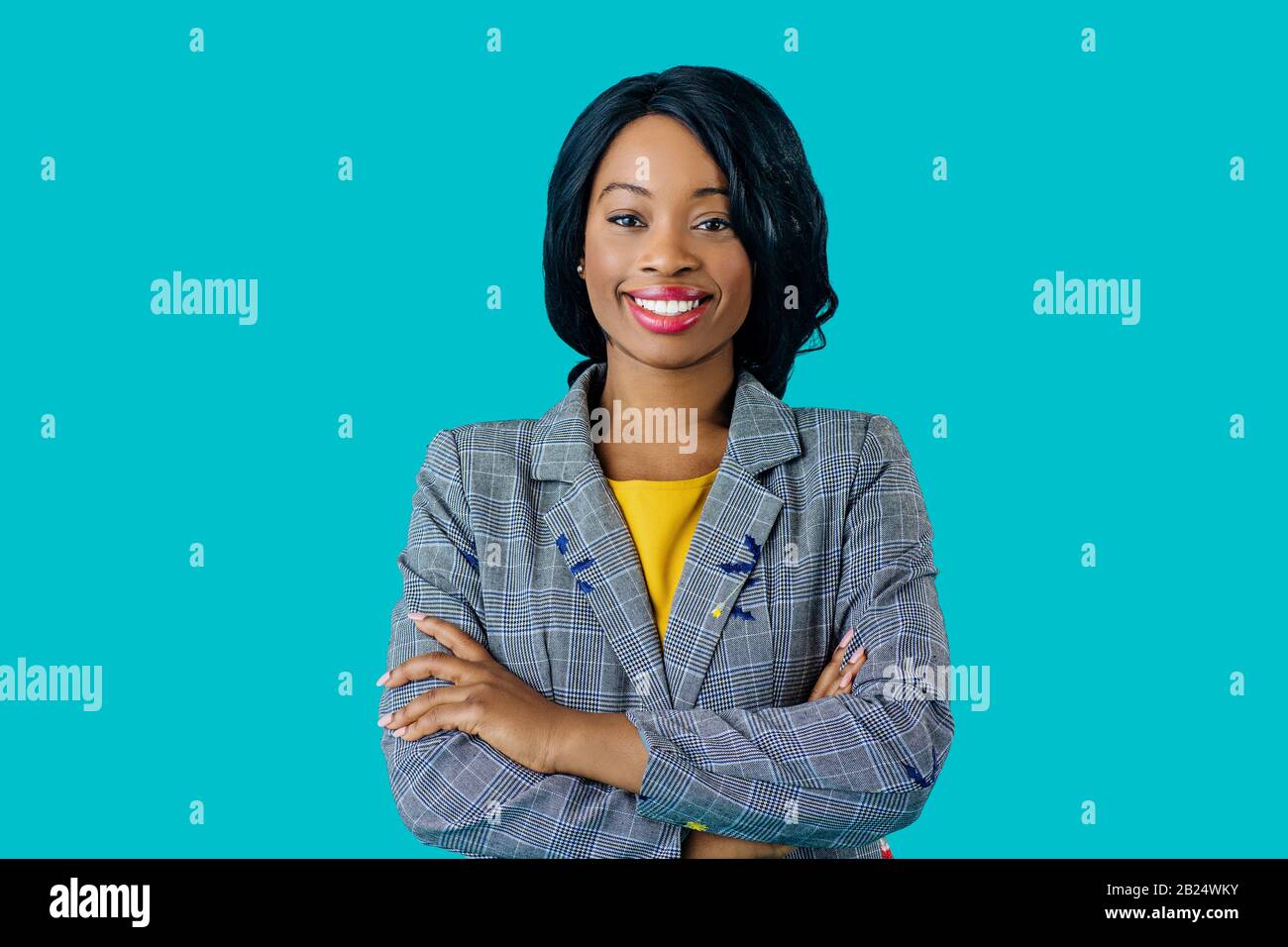 Portrait d'une jeune femme souriante heureuse dans une veste d'affaires avec des bras croisés isolés sur bleu Banque D'Images