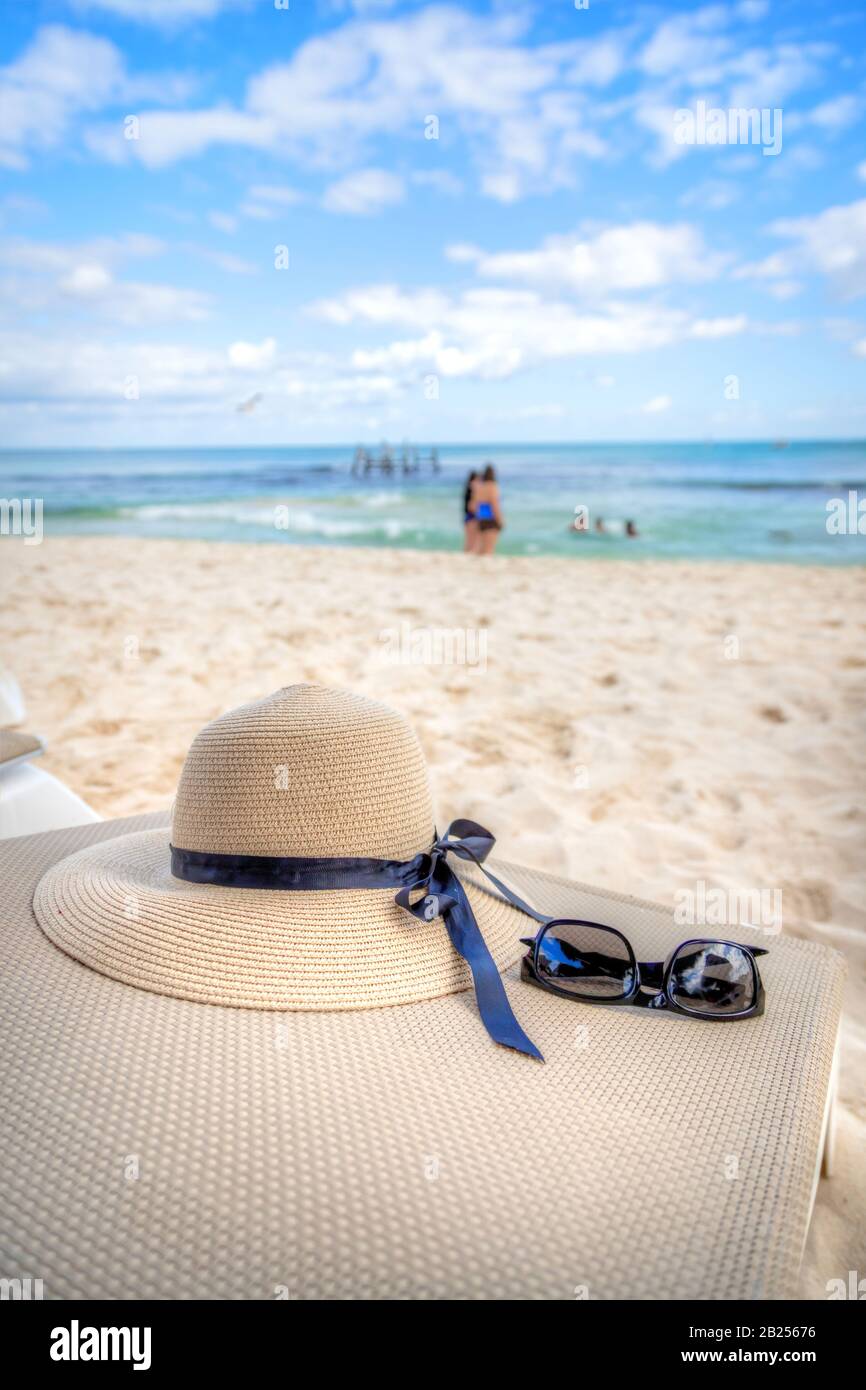 Thème de vacances avec lunettes de soleil et chapeau dans une plage tropicale fond avec mer et ciel bleu. Espace de copie. Banque D'Images