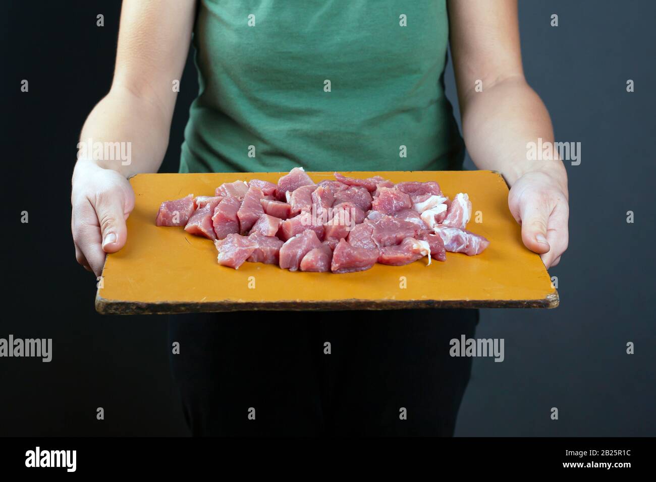 fille tenant la viande hachée sur une préparation de planche en bois pour la cuisson sur fond sombre. Banque D'Images