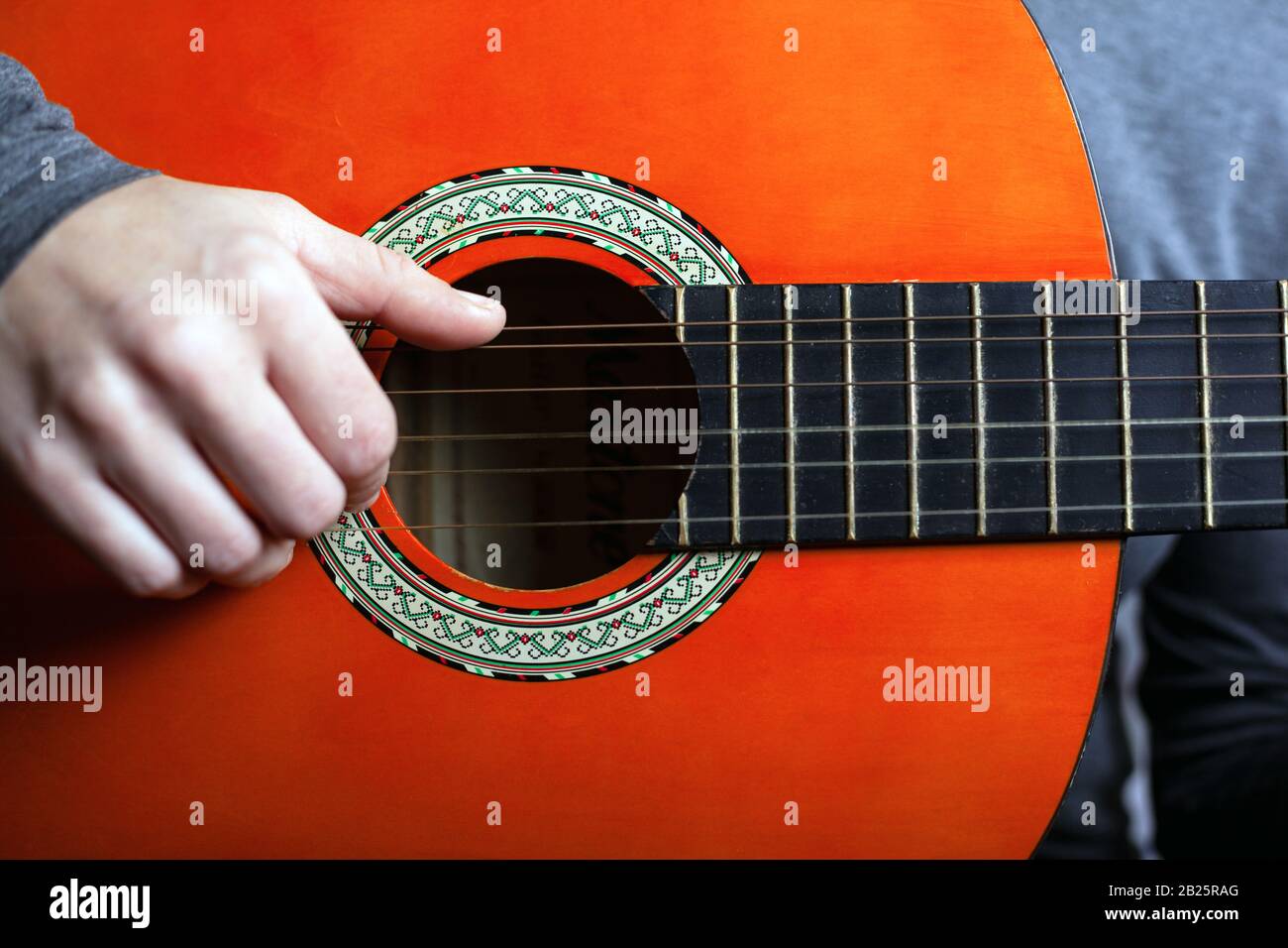homme jouant avec une guitare acoustique orange. l'art de jouer un instrument de musique classique à cordes. Banque D'Images