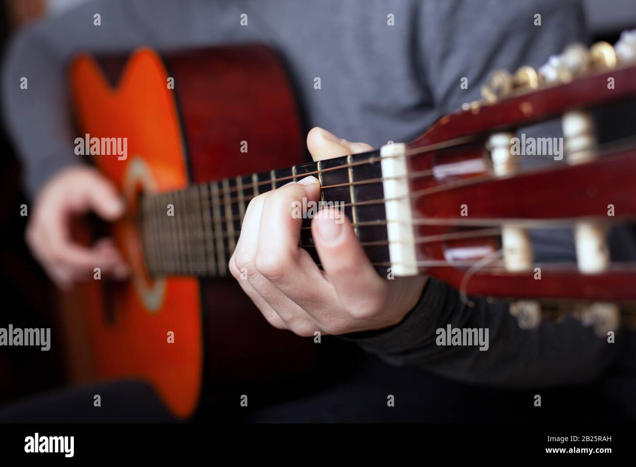 homme jouant avec une guitare acoustique orange. l'art de jouer un instrument de musique classique à cordes. Banque D'Images