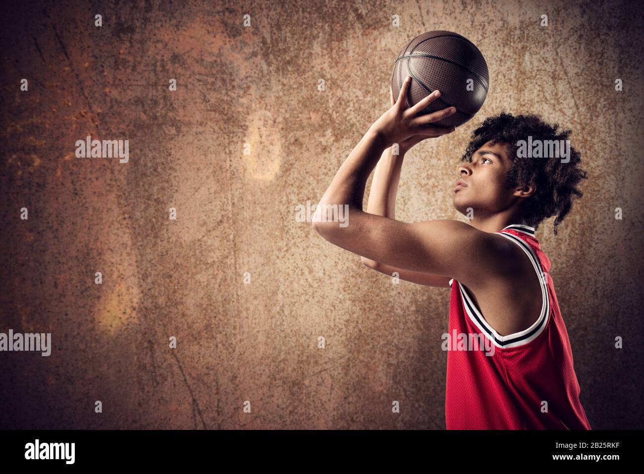 Le joueur de basket-ball jette le ballon sur fond brun grunge Banque D'Images