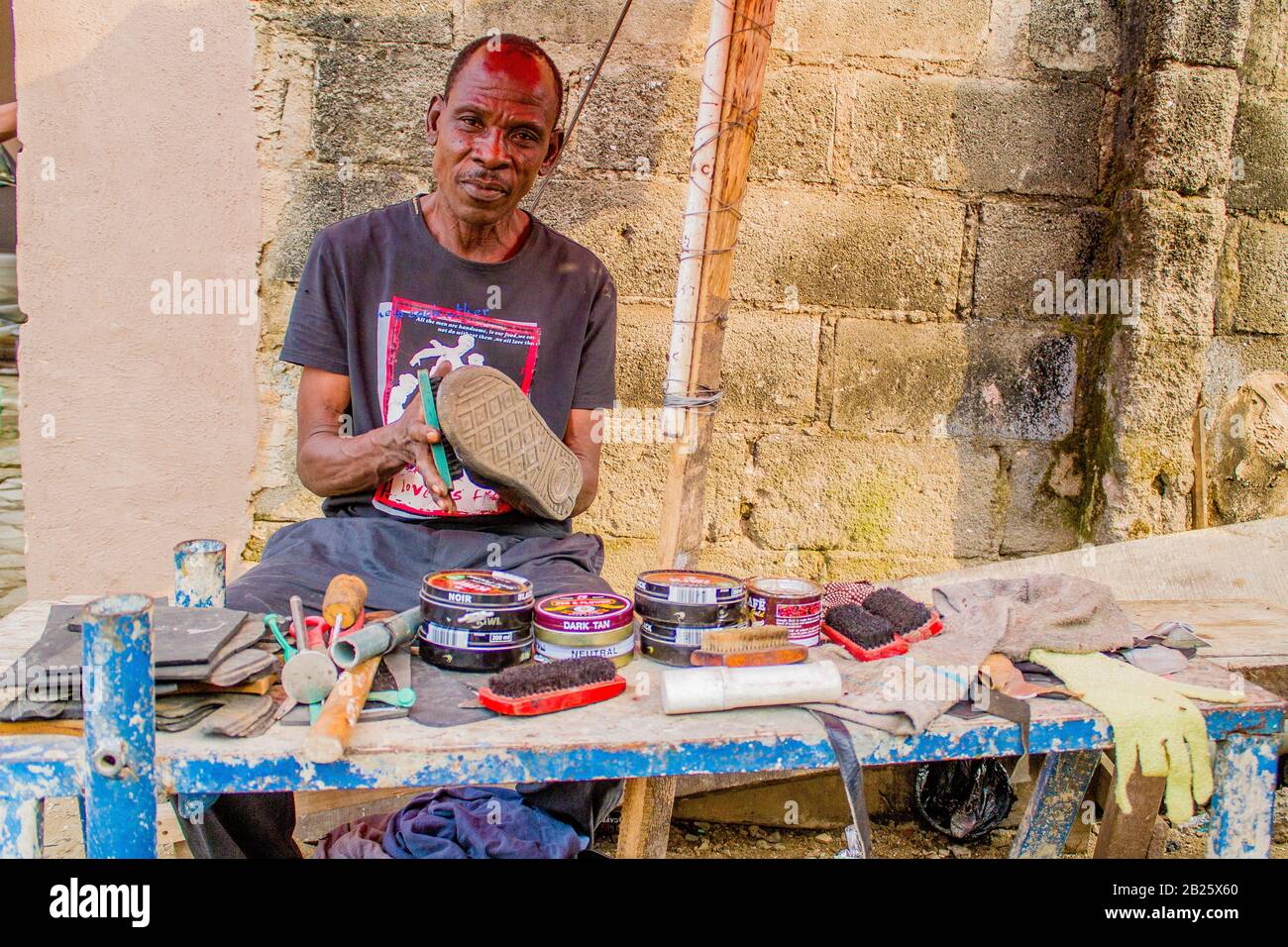 Un mousqueton et un réparateur de chaussures au travail dans une rue au Nigeria. Banque D'Images