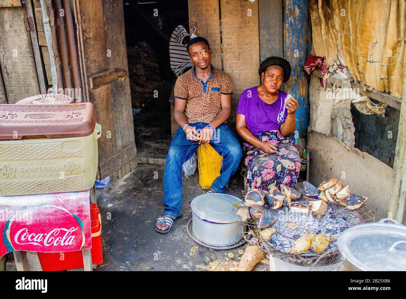 Une mère et un fils vendent du yam rôti et du poisson dans une rue de Lagos, au Nigeria. Banque D'Images