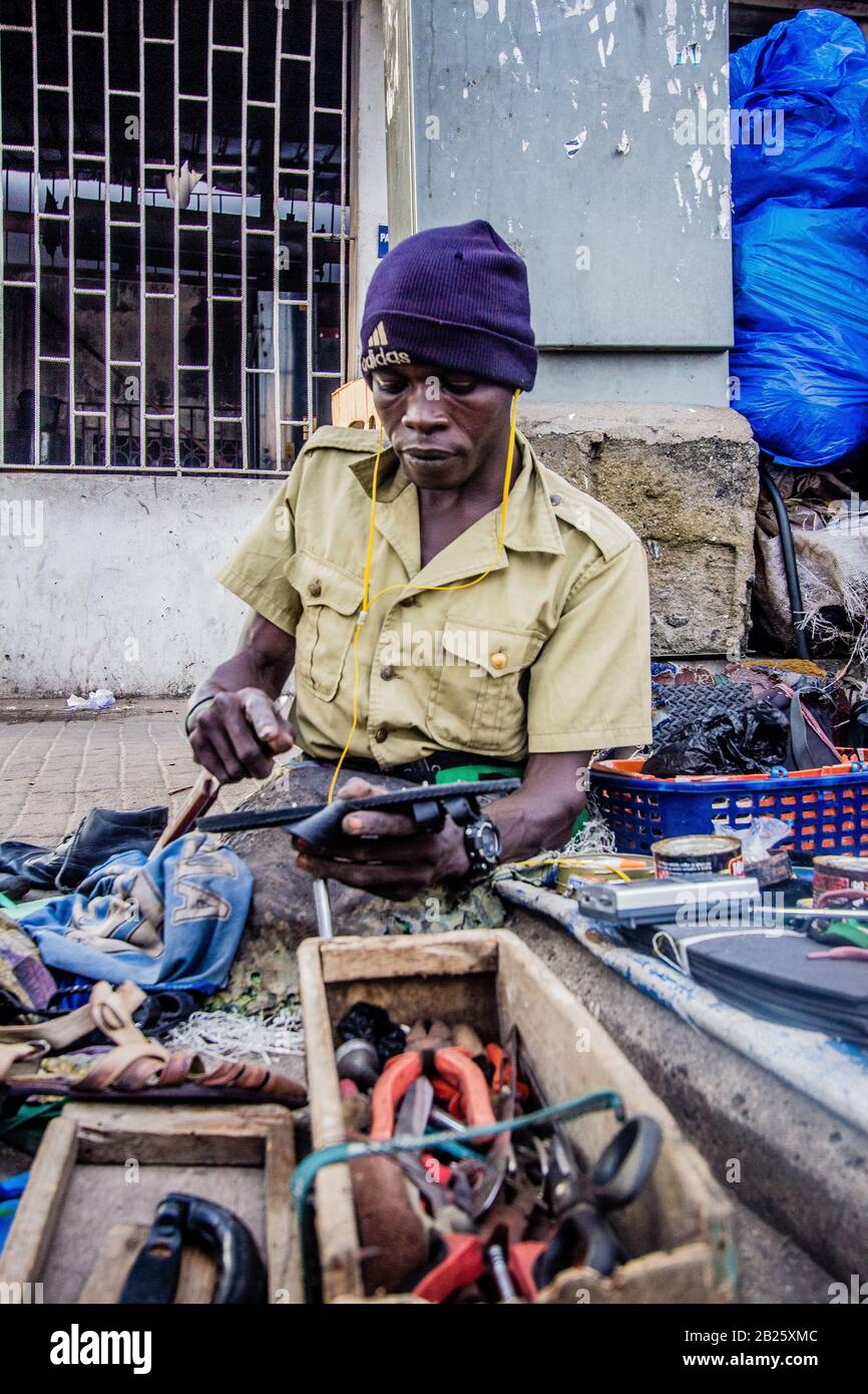 Un réparateur de chaussures dans une rue au Nigeria. Banque D'Images