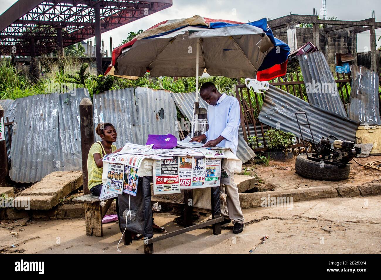 Les gens arrêtent de lire les journaux sur un kiosque à journaux situé dans une rue de Lagos, au Nigeria. Banque D'Images