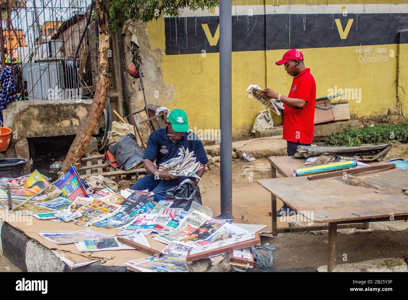 Les gens arrêtent de lire les journaux sur un kiosque à journaux situé dans une rue de Lagos, au Nigeria. Banque D'Images