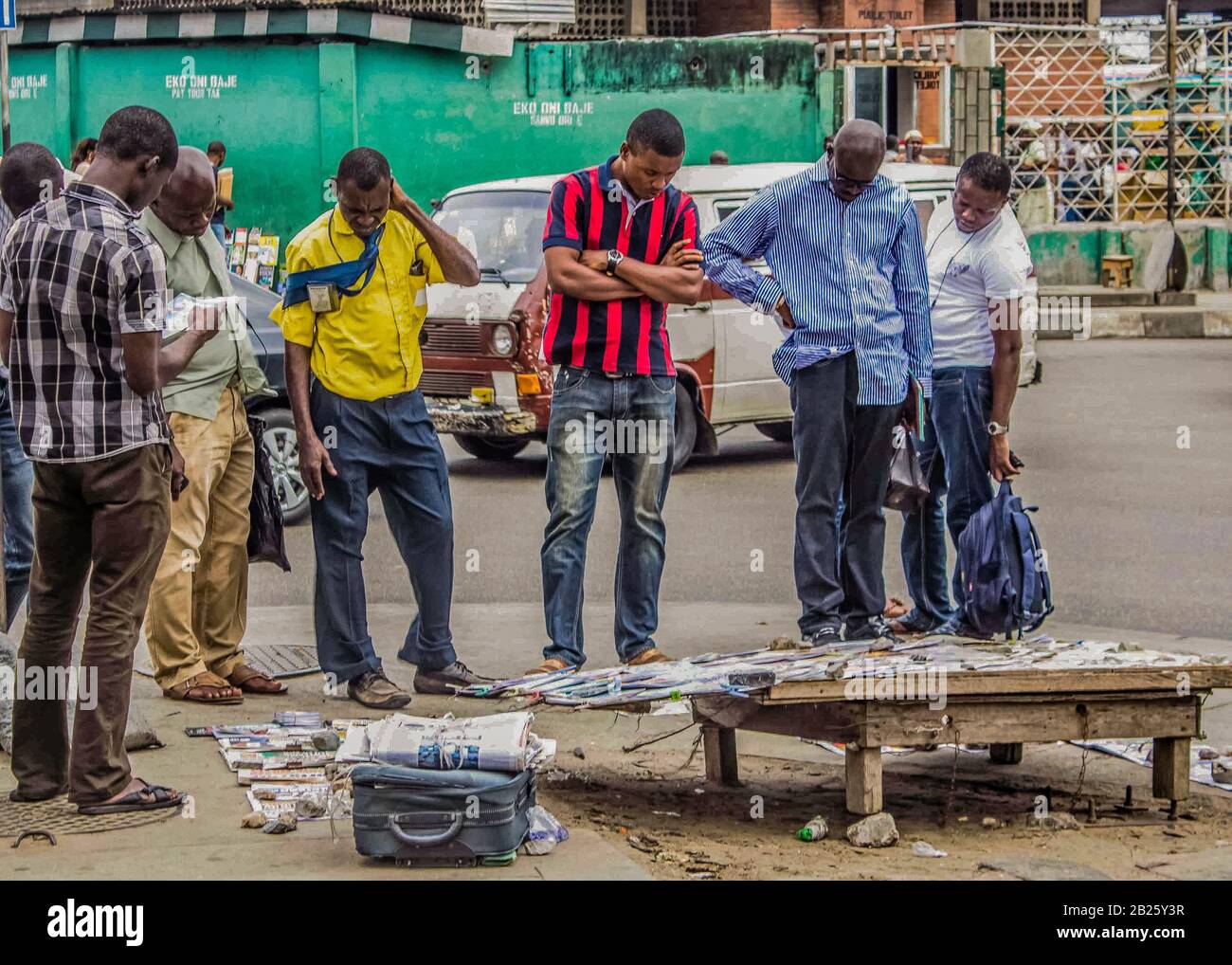 Les gens arrêtent de lire les journaux sur un kiosque à journaux situé dans une rue de Lagos, au Nigeria. Banque D'Images