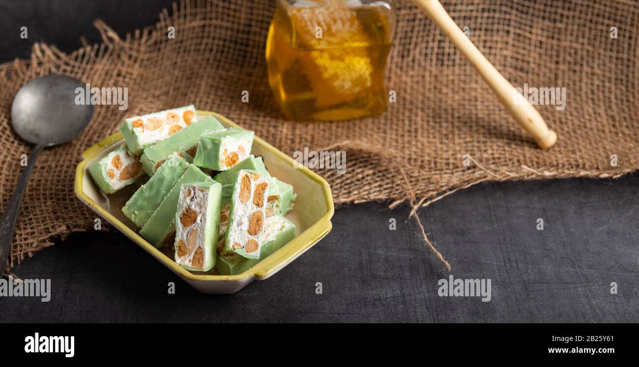 Nougat bio faites avec du miel, pistache, noisette, noix et amandes, sur un fond sombre. rustique Banque D'Images