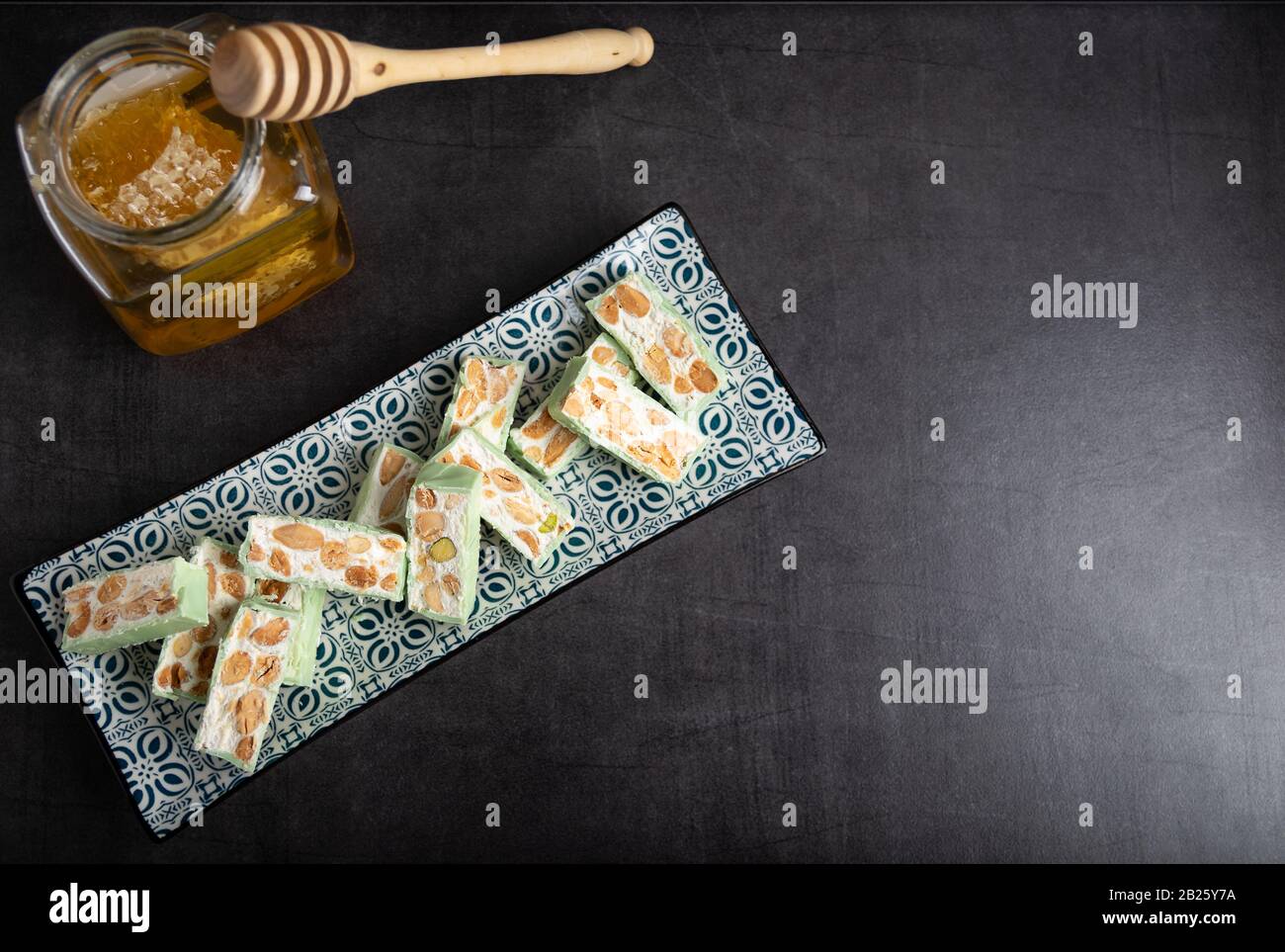 Nougat bio faites avec du miel, pistache, noisette, noix et amandes, sur un fond sombre. rustique Banque D'Images