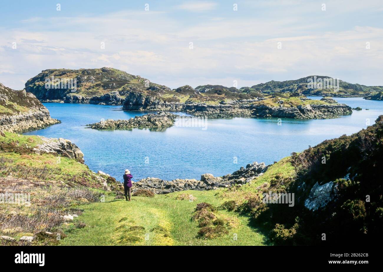 Walker et petite île rocheuse d'Eilean Rosaidh et côte près de Cromor sur la côte est de l'île de Lewis dans les Hébrides extérieures, Ecosse, Royaume-Uni Banque D'Images