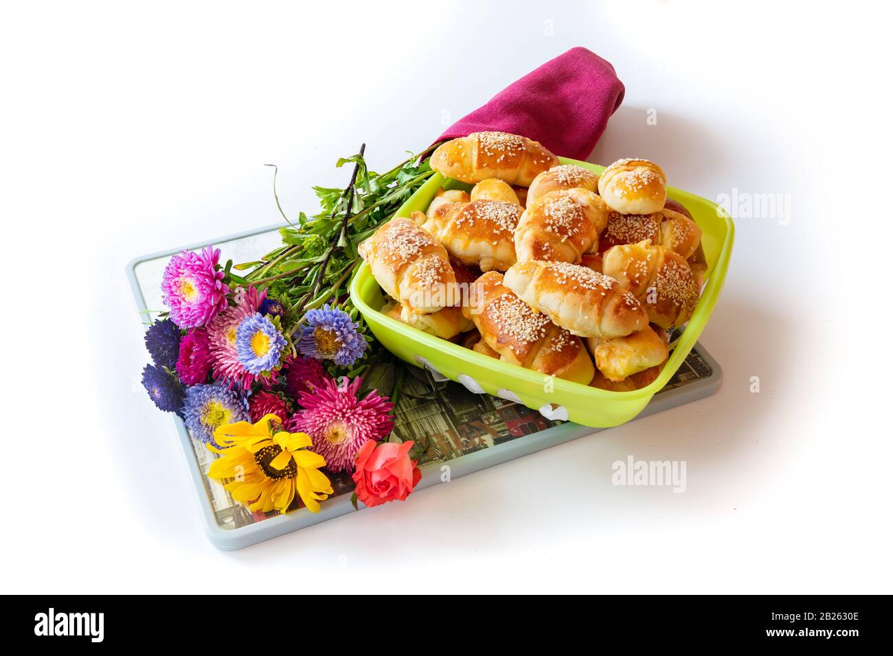 Petits pains au fromage, frais, croquants et chauds, servis avec amour, avec un grand bouquet de fleurs de champ, sur fond blanc Banque D'Images