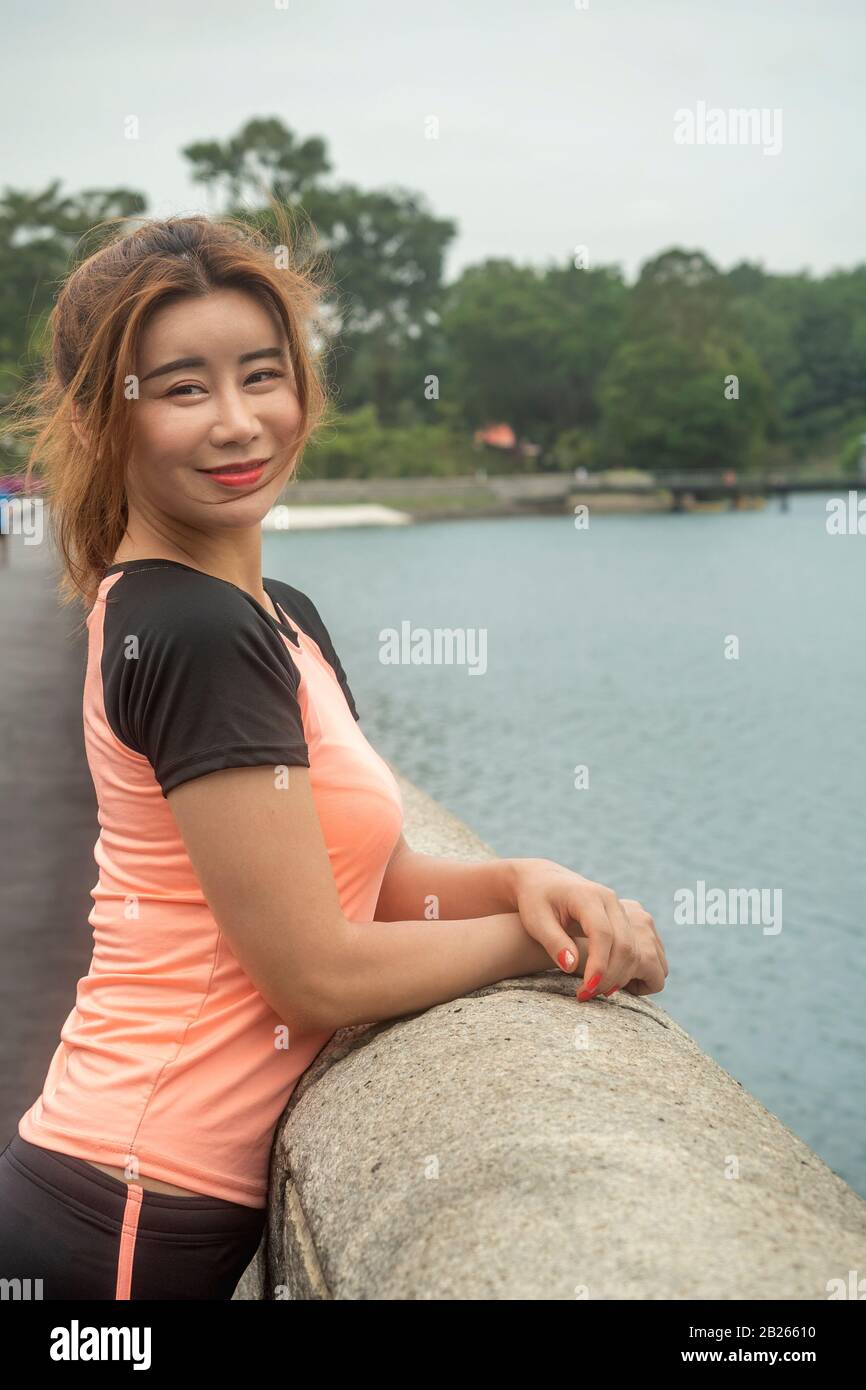 Une fille chinoise asiatique dans sa tenue de sport souriant et posant pour appareil photo après avoir terminé la séance d'entraînement du matin Banque D'Images