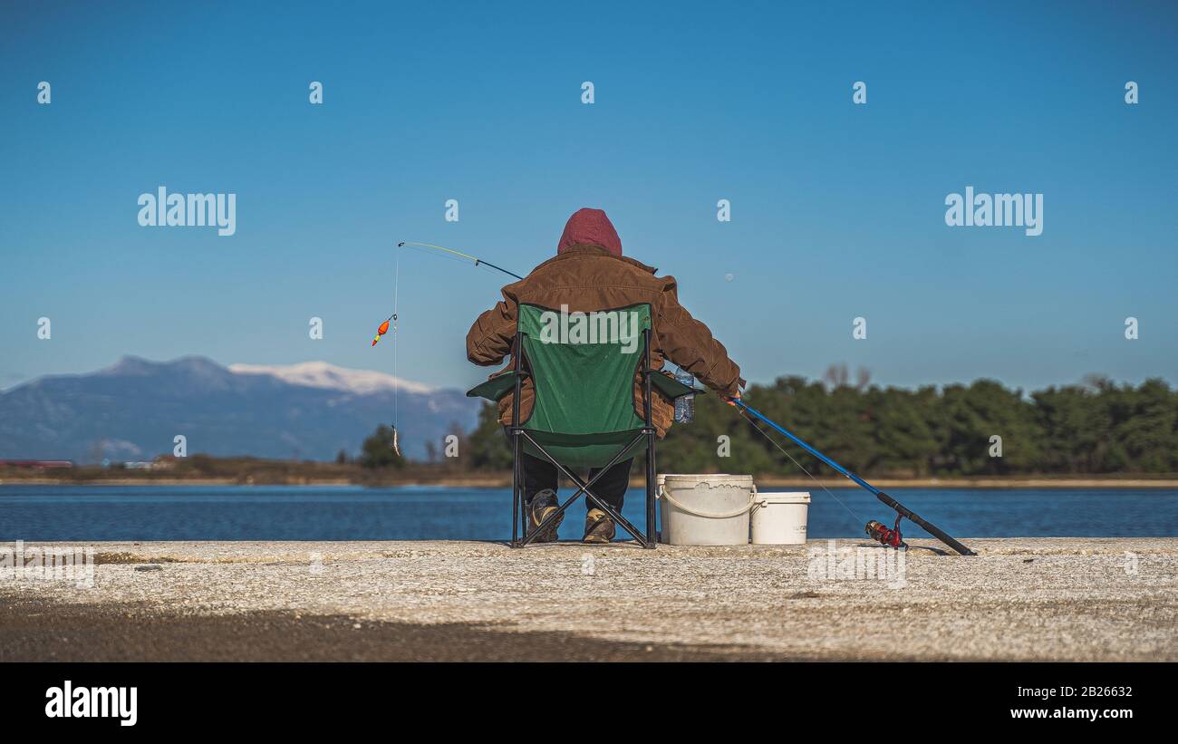 pauvre pêcheur en action avec le poteau de pêche à la jetée Banque D'Images