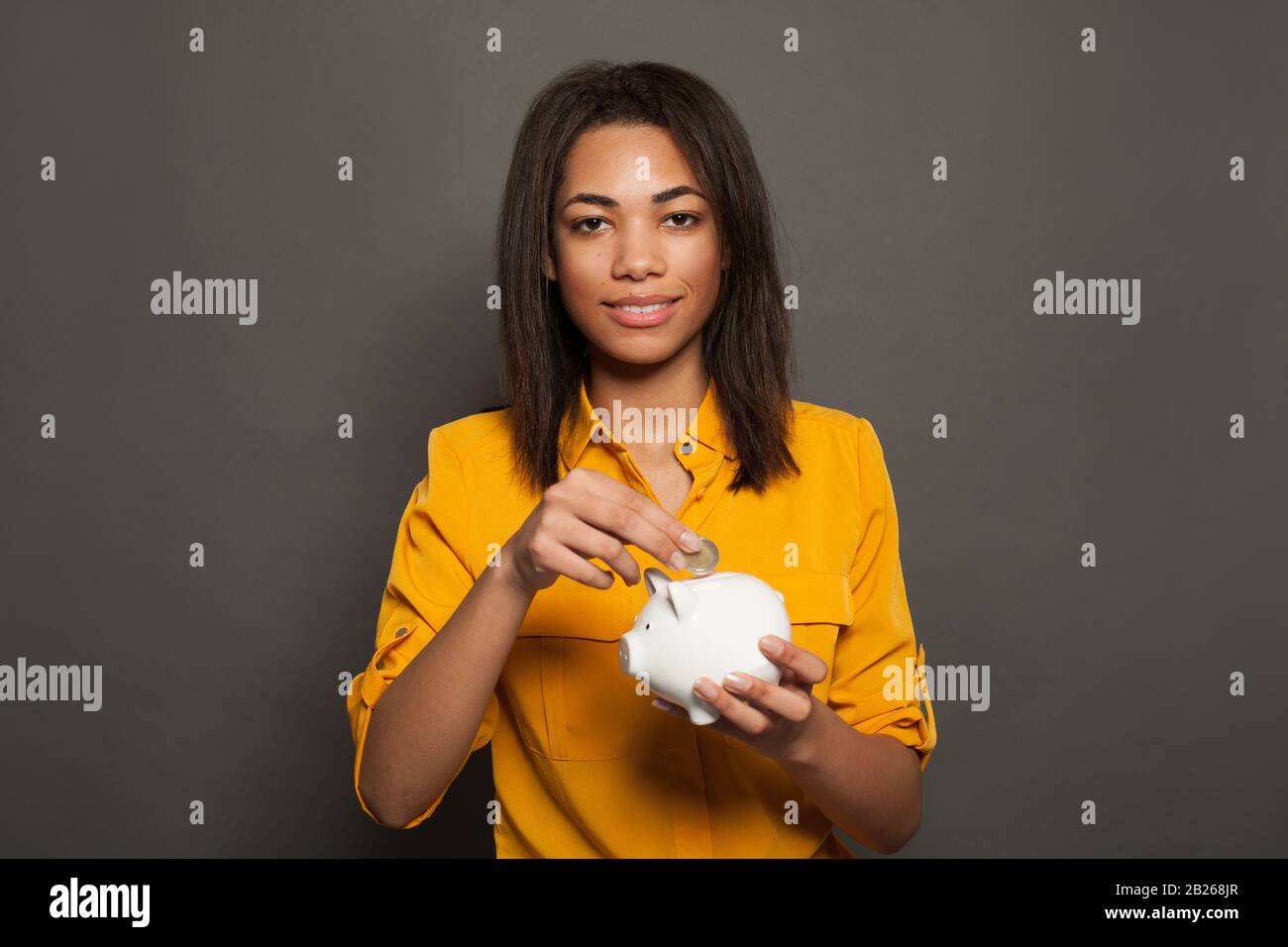 Smart fille noire mettant en piggy banque une pièce de monnaie Banque D'Images