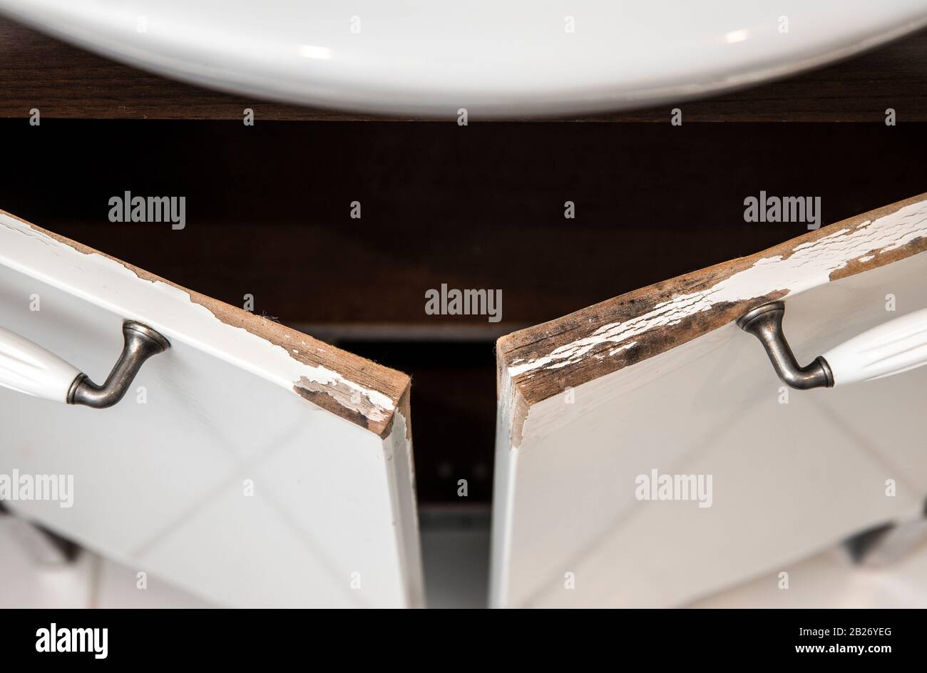Meuble-lavabo de salle de bains en MDF blanc brillant endommagé par l'eau avec moulure. Concept d'état de salle de bains humide. Banque D'Images