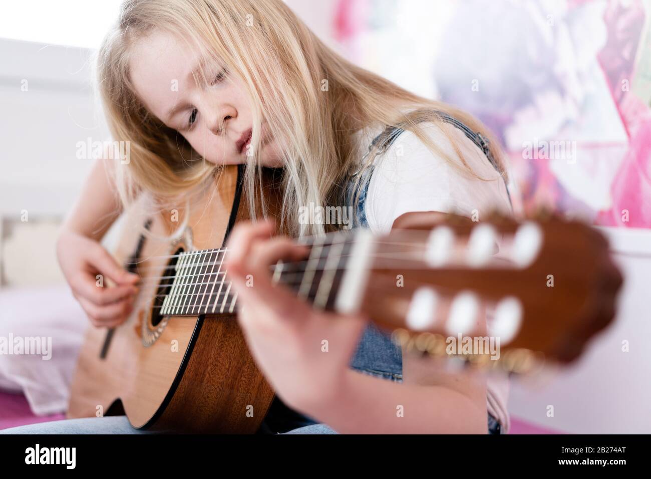 Génération Z - une jeune fille joue de la guitare dans sa chambre. Banque D'Images