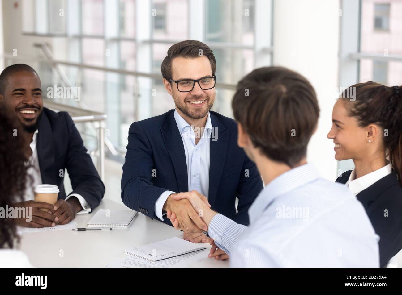 Un homme d'affaires souriant et heureux est en train de se faire une poignée de main avec un partenaire commercial pour un accord Banque D'Images