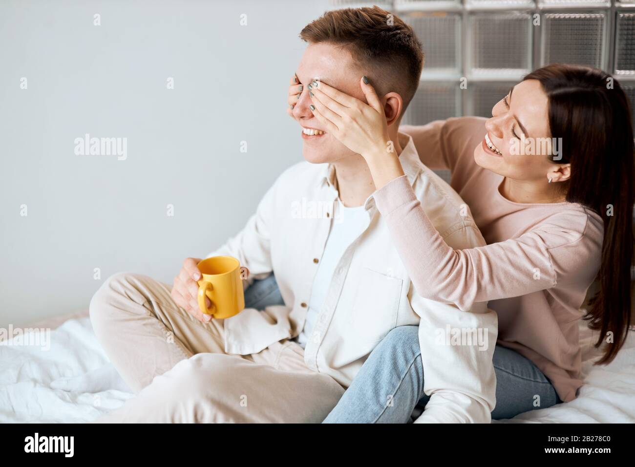 Couple ayant du plaisir dans la chambre Belle jeune fermeture des yeux de son petit ami, fille faisant la surprise pour son mari à l'anniversaire, le bonheur, positif f Banque D'Images