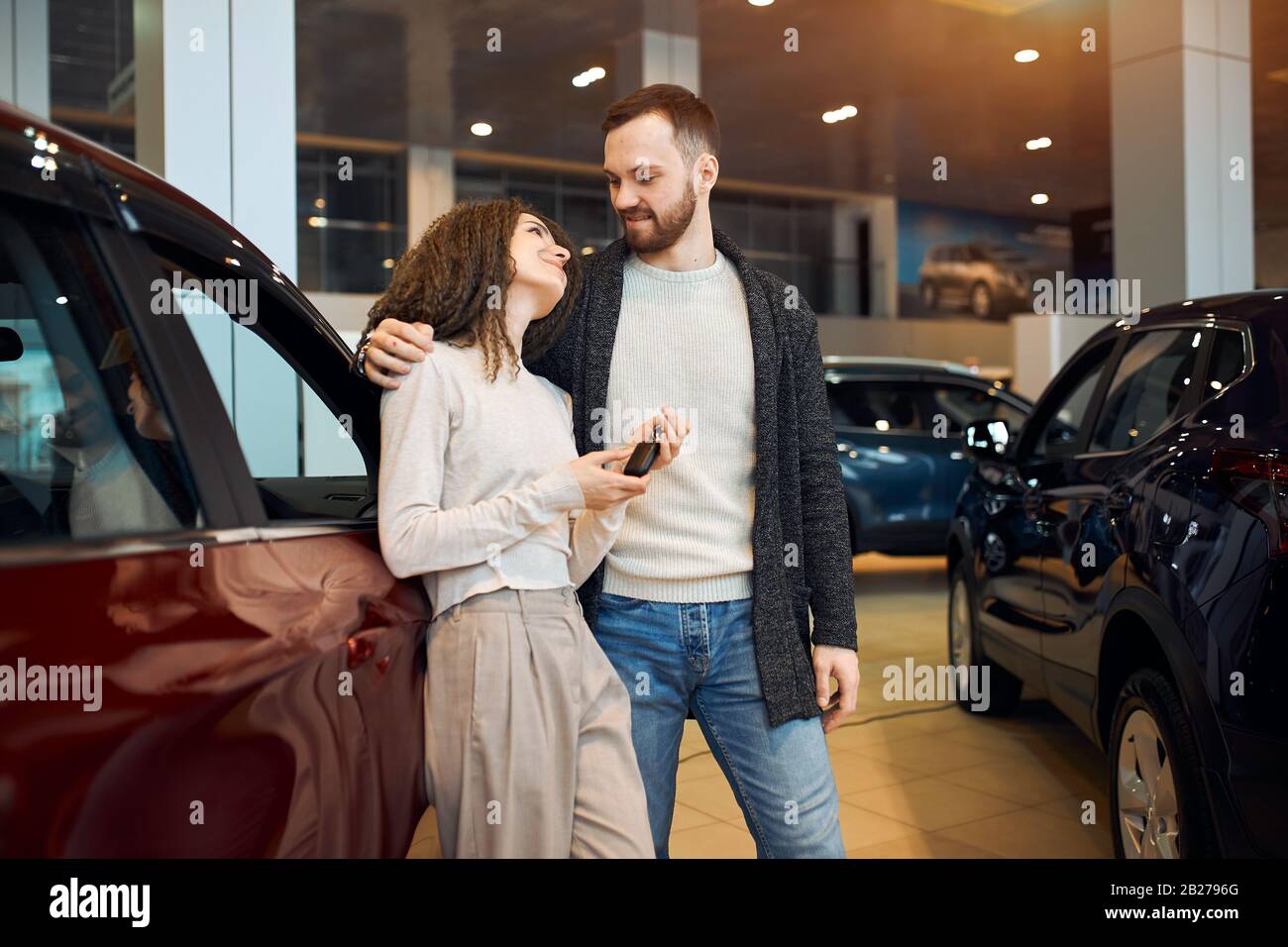 heureuse jeune femme remerciant son mari pour son présent, merci. gros plan photo. La famille excitée achète une voiture chez le concessionnaire Banque D'Images