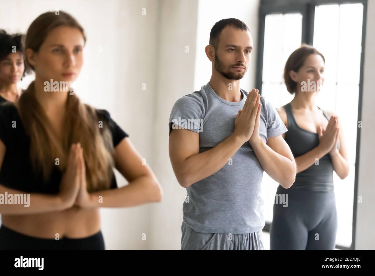 Les gens se tenant à l'intérieur avec des mains repliées montrant le geste Namaste Banque D'Images