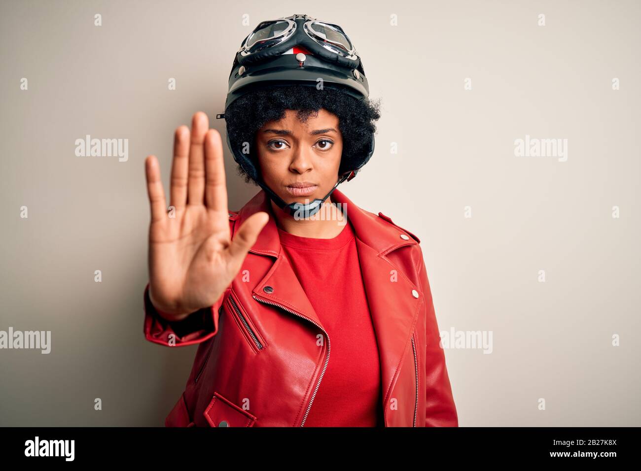 Jeune femme afro-motocycliste africaine avec des cheveux bouclés portant un  casque de moto qui arrête de chanter avec la paume de la main. Expression  d'avertissement WIT Photo Stock - Alamy