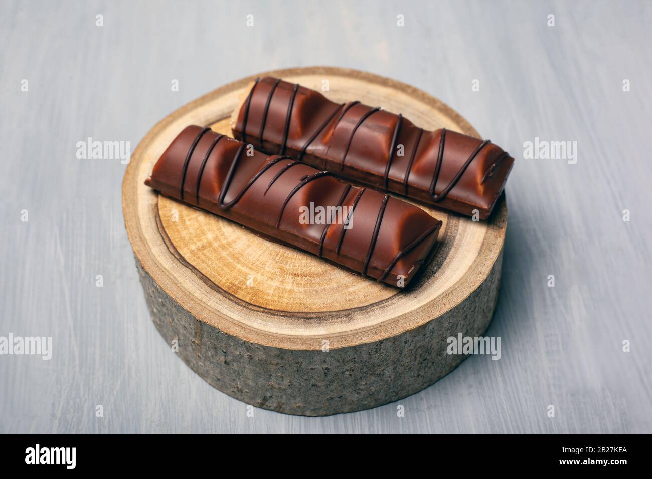 bâtonnets de chocolat sur un stand de bois forestier sur un fond gris bonbons pour la joie de près. Banque D'Images